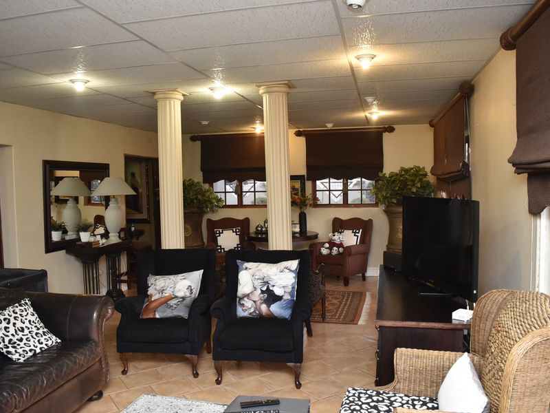 Spacious living area featuring decorative columns, tiled flooring, and a drop ceiling with recessed lighting.