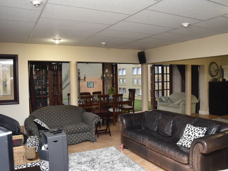 Spacious open-plan living and dining area featuring tiled flooring, structural columns, and direct access to an outdoor patio through multiple sets of french doors.