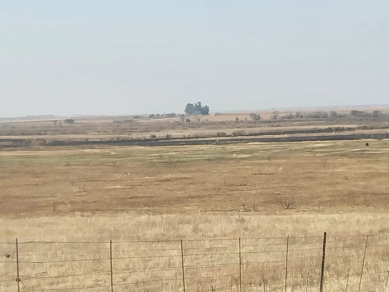 A wide-angle view of the expansive rural landscape and open fields surrounding the small holding property.