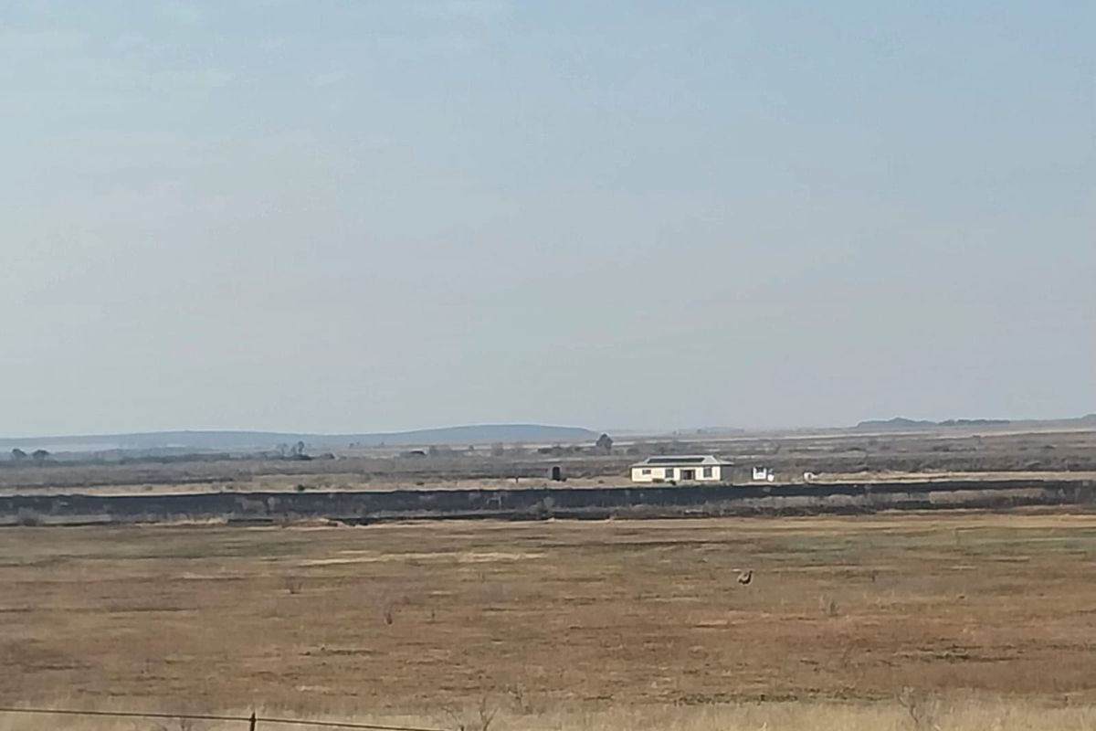 A distant aerial view of a small holding property situated within a vast, open rural landscape.