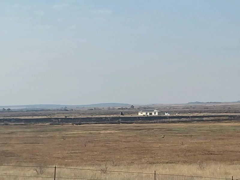 A distant aerial view of a small holding property situated within a vast, open rural landscape.