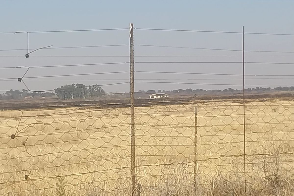 A distant view of the property landscape featuring dry veld and wire perimeter fencing.