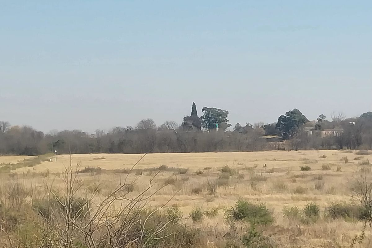 A wide-angle view of the open landscape and natural vegetation surrounding the small holding property.