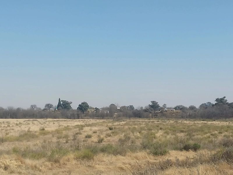 A wide-angle view of the open landscape and natural vegetation surrounding the small holding property.