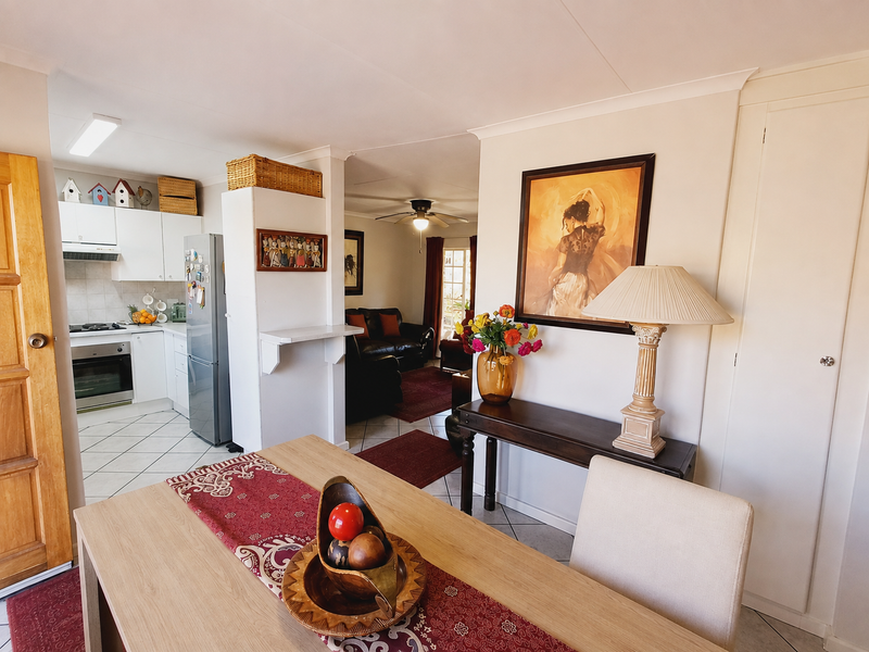 Open-plan living area featuring a functional kitchen with built-in appliances, tiled flooring, and a seamless flow into the adjacent living space.