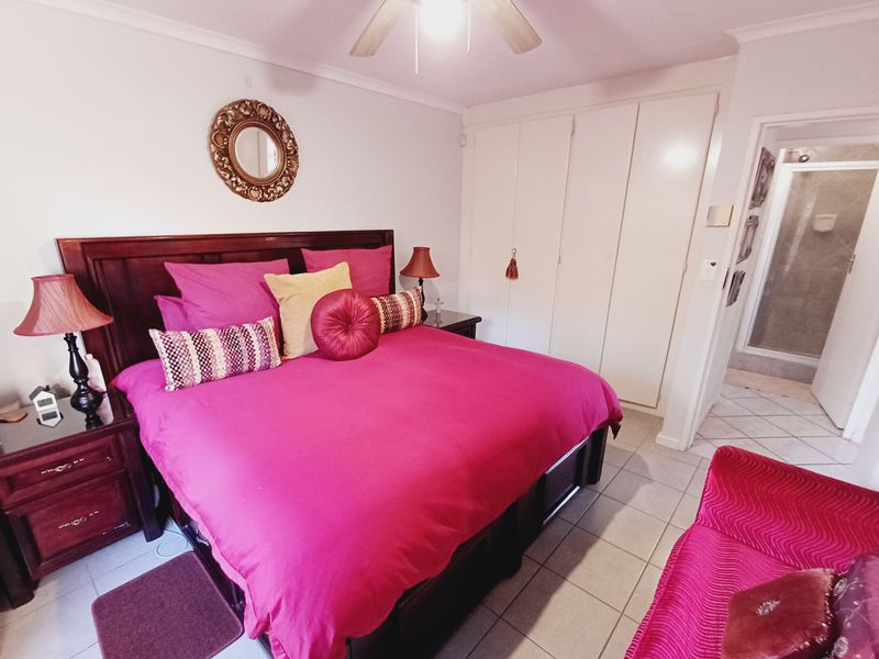 A bedroom featuring built-in cupboards, tiled flooring, and an en-suite bathroom, providing a functional and well-connected living space.