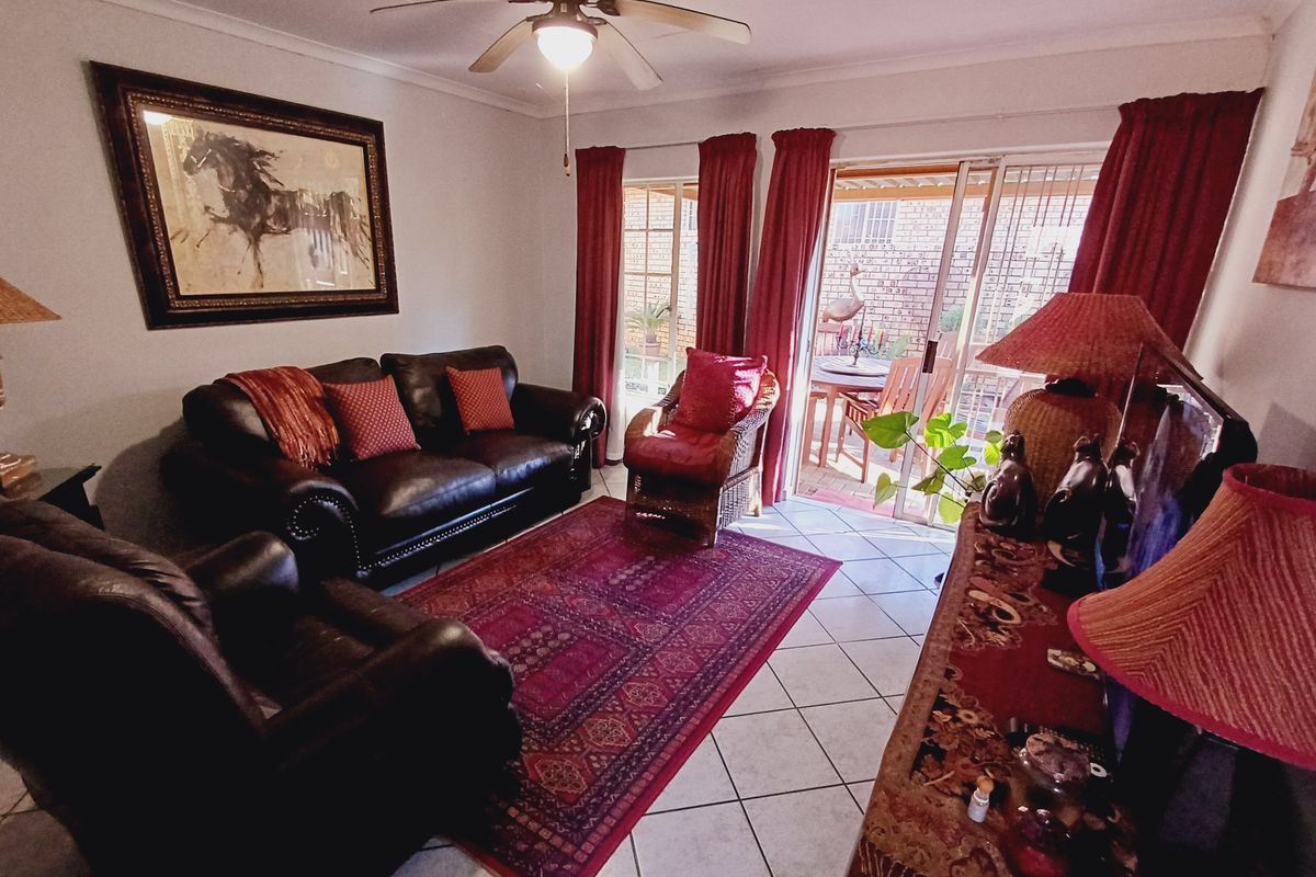A comfortable living room featuring ceramic floor tiles, a ceiling fan, and sliding glass doors providing direct access to the outdoor patio area.