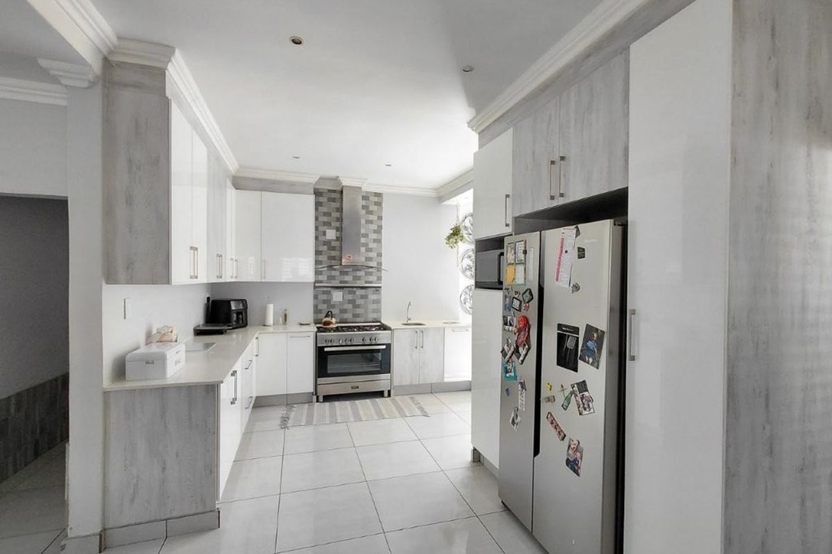 Modern kitchen featuring light wood-grain and white cabinetry, tiled flooring, a gas stove with extractor fan, and a tiled backsplash.