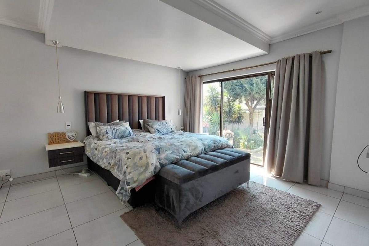 Spacious bedroom featuring tiled flooring, a recessed ceiling, and a large sliding glass door providing direct access to the garden.