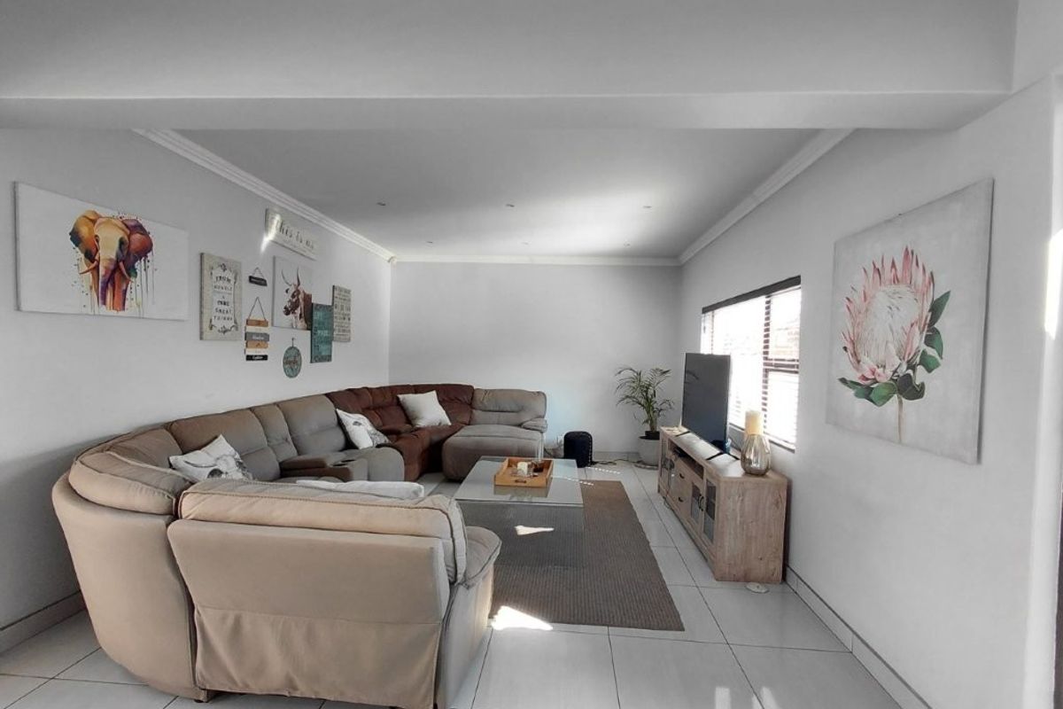 A bright and spacious living room featuring neutral tiled flooring, recessed ceiling lighting, and coved cornicing, providing a comfortable and well-maintained living area.