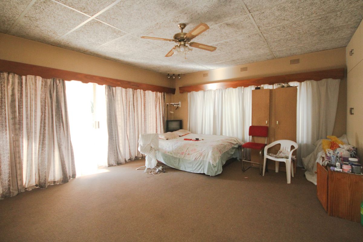 Spacious bedroom featuring built-in cupboards, a ceiling fan, and carpeted flooring, offering a blank canvas for renovation and modernization.