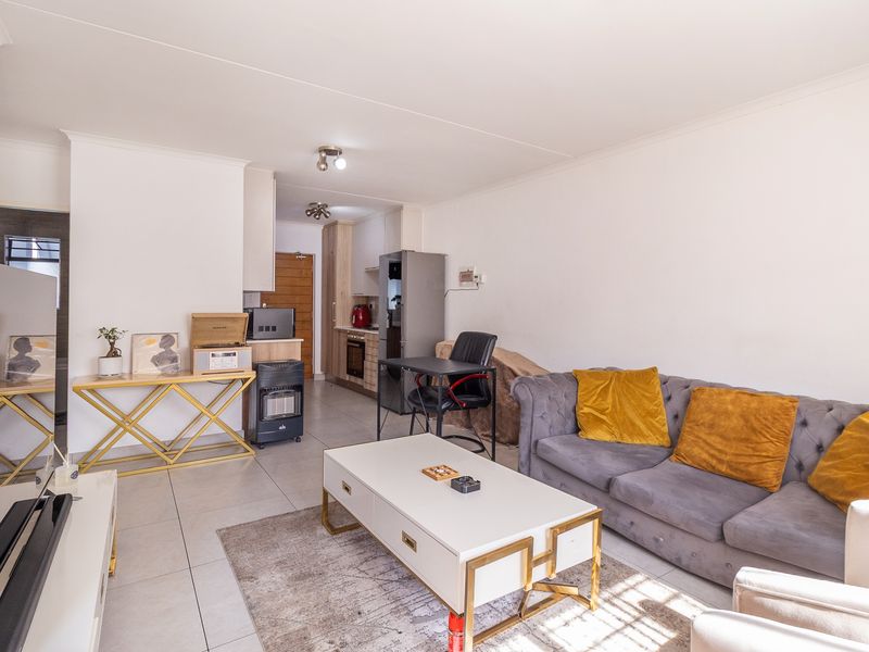 An open-plan living area featuring tiled flooring and a compact kitchen with built-in cabinetry and oven, creating a functional and connected living space.