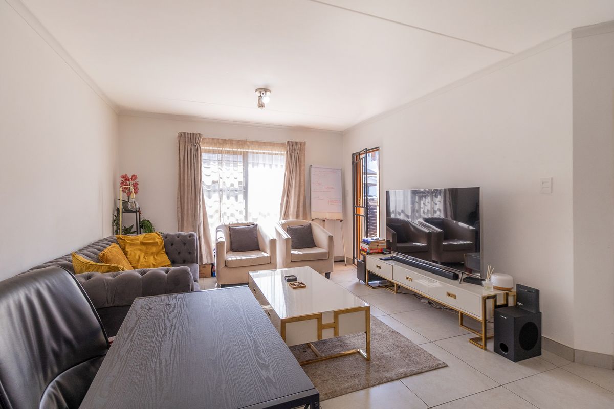 A bright and well-maintained living room featuring neutral tiled flooring and direct access to an outdoor area through a sliding glass door.