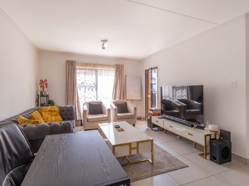 A bright and well-maintained living room featuring neutral tiled flooring and direct access to an outdoor area through a sliding glass door.