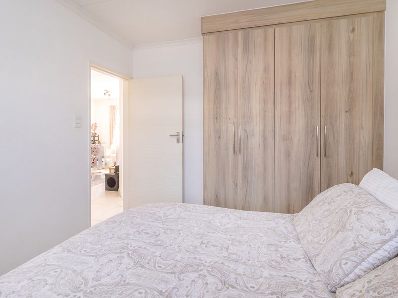 A well-maintained bedroom featuring light wood-finish built-in cupboards and a clean, neutral interior design.