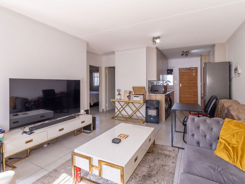 Open-plan living area featuring tiled flooring, integrated kitchen cabinetry, and neutral finishes, creating a functional and connected space for daily living.