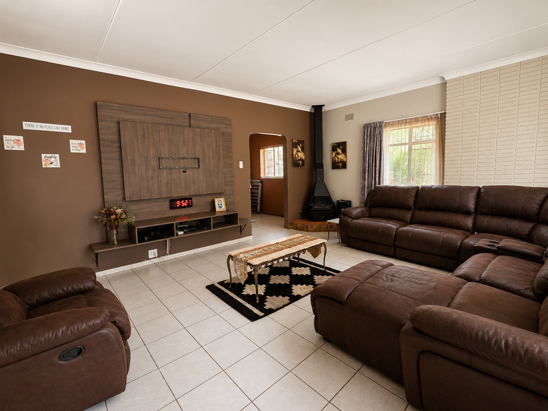 Spacious living room featuring tiled floors, a brick feature wall, and a modern freestanding fireplace, offering a comfortable and functional family space.