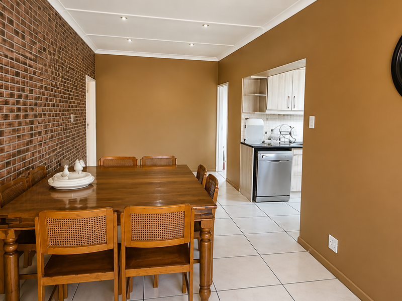 Open plan dining area featuring an exposed brick wall and tiled flooring, with a view into the adjacent kitchen space.