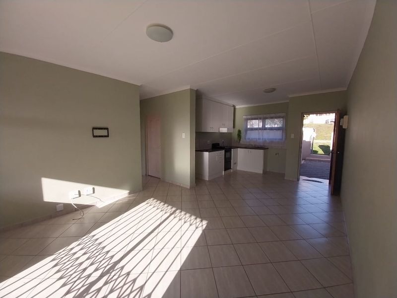 An open-plan living and kitchen area featuring tiled flooring, built-in cabinetry, and direct access to an outdoor space.