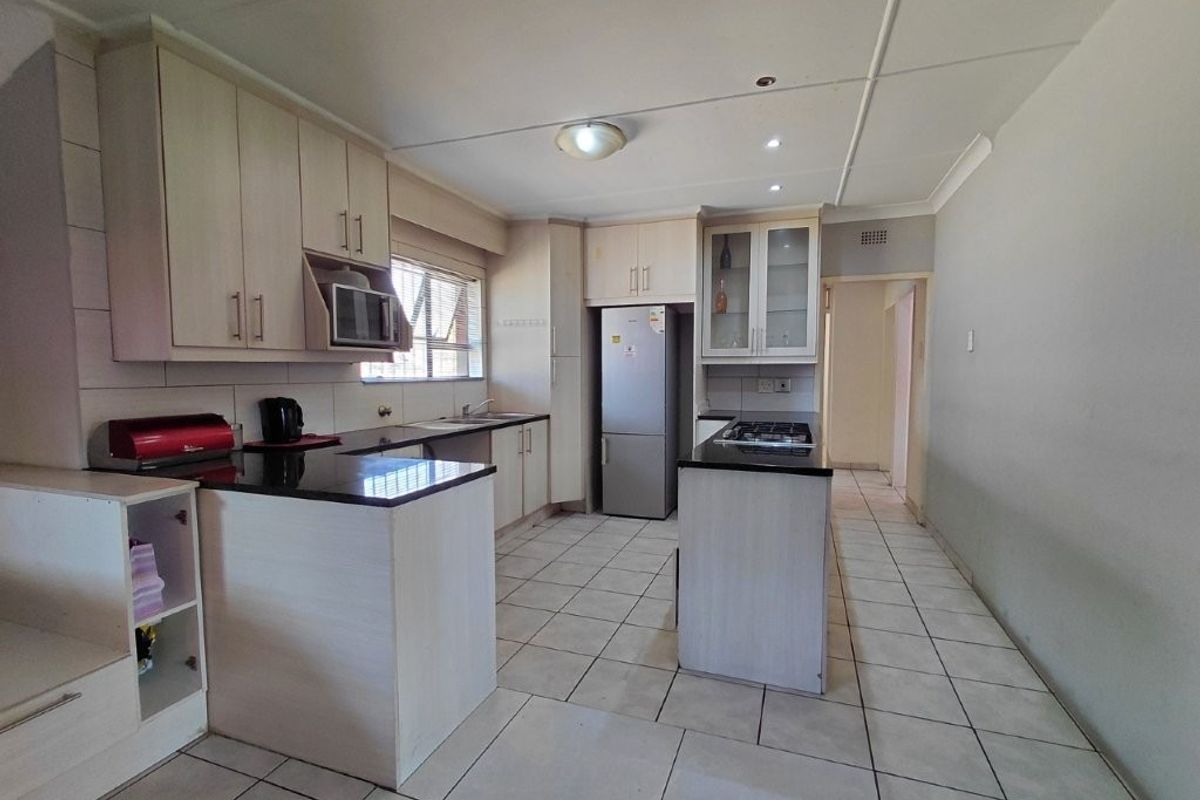 A functional kitchen featuring light-toned built-in cabinetry, granite countertops, a gas hob, and tiled flooring, offering a clean and practical workspace.