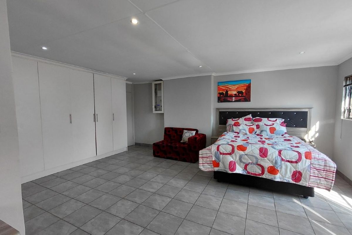 Spacious bedroom featuring neutral tiled flooring, extensive built-in cupboard storage, and recessed ceiling lighting.