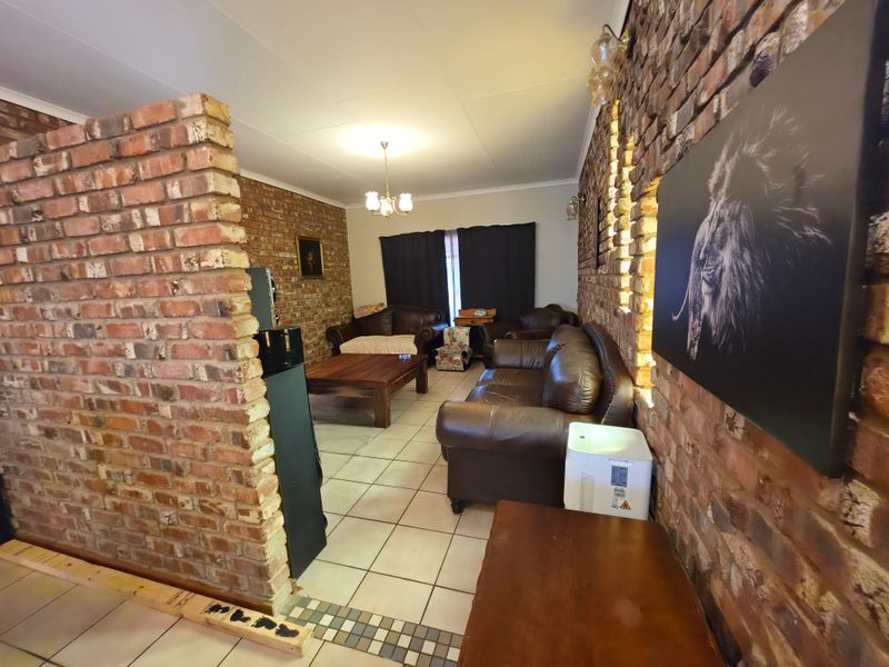 Living room featuring exposed brick walls, tiled flooring, and integrated wall lighting, offering a rustic aesthetic with potential for modern updates.