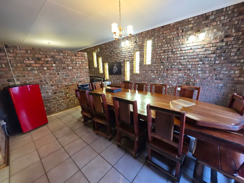 Spacious dining room featuring a prominent exposed brick wall, ceramic tiled flooring, and traditional feature lighting.