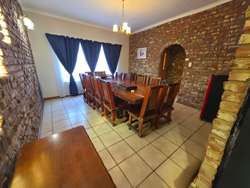 Spacious dining room featuring rustic exposed brick walls, ceramic tiled flooring, and a distinctive arched entryway leading to adjacent living areas.