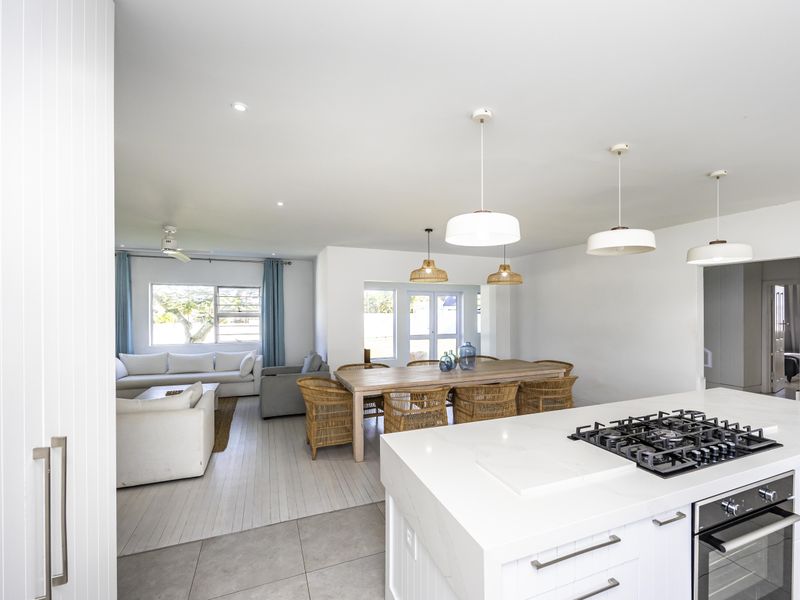 Spacious open-plan living and dining area featuring a modern kitchen island with a gas cooktop and built-in oven, complemented by contemporary pendant lighting.