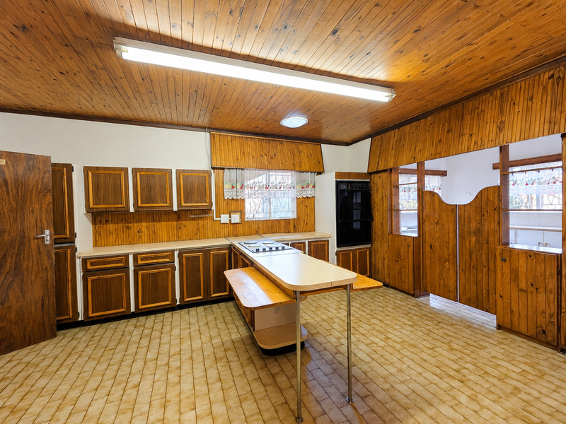 Spacious kitchen featuring extensive timber cabinetry, built-in oven, electric hob, and tiled flooring, offering a classic layout ready for modern updates.