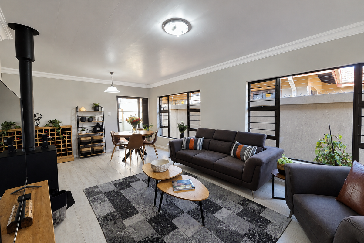 Spacious living area featuring laminate flooring, a modern wood-burning fireplace, and large windows that provide ample natural light.