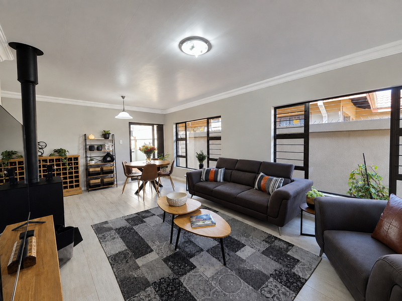 Spacious living area featuring laminate flooring, a modern wood-burning fireplace, and large windows that provide ample natural light.