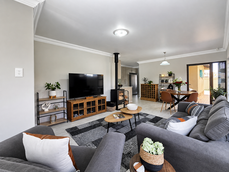 Spacious open-plan living and dining area featuring a modern freestanding fireplace, crown molding, and direct access to an outdoor patio space.