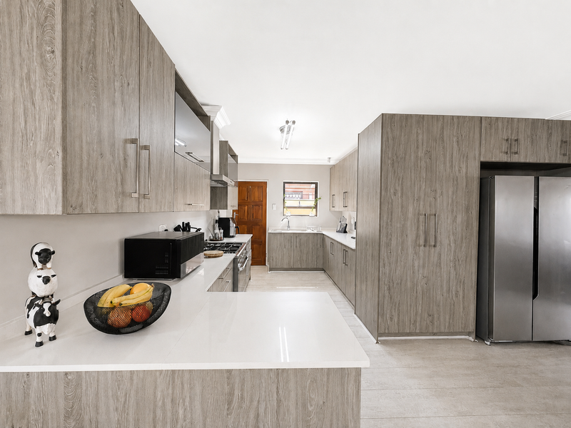 Modern kitchen featuring wood-grain cabinetry, stone countertops, integrated appliances, and a functional layout with ample storage and workspace.