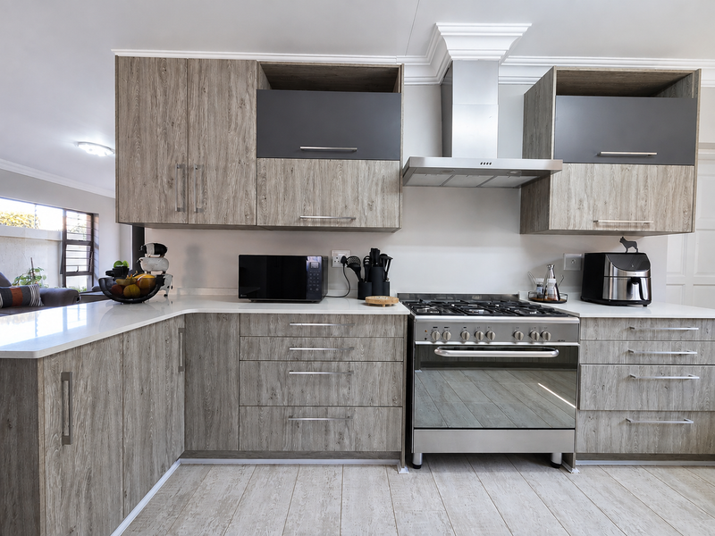 Modern kitchen featuring wood-grain cabinetry, quartz countertops, and a stainless steel gas stove with an integrated extractor fan.