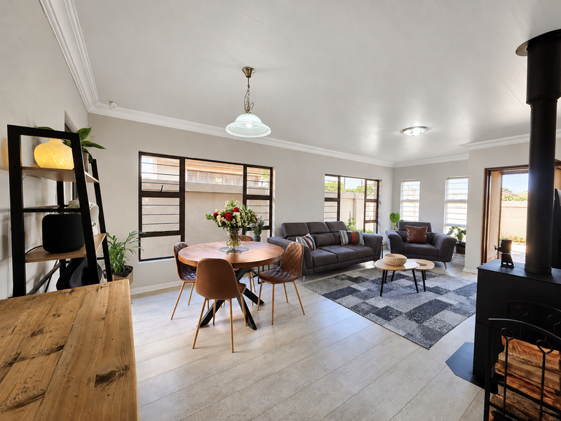 Spacious living area featuring light laminate flooring, cove cornicing, and a prominent wood-burning fireplace, offering a bright and comfortable atmosphere.