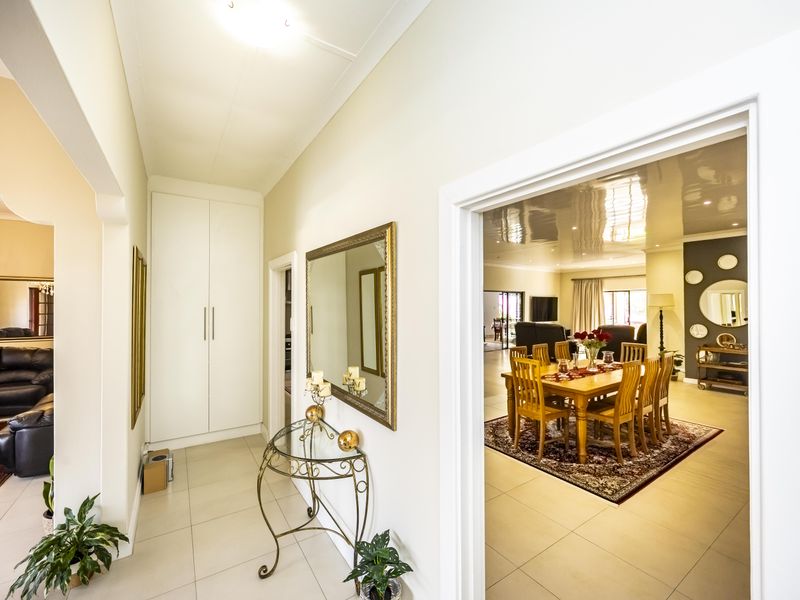 A bright, tiled entrance hallway featuring a built-in storage cupboard and seamless transition into the adjacent dining and living areas.