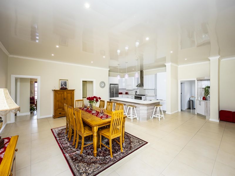 Spacious open-plan living area featuring a modern kitchen with a central island, sleek cabinetry, and neutral tiled flooring throughout.