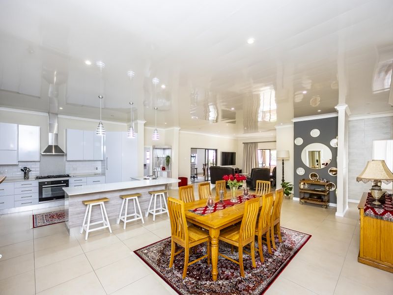 Spacious open-plan living area featuring a modern kitchen with island, glossy ceiling finish, and seamless flow to the dining space.