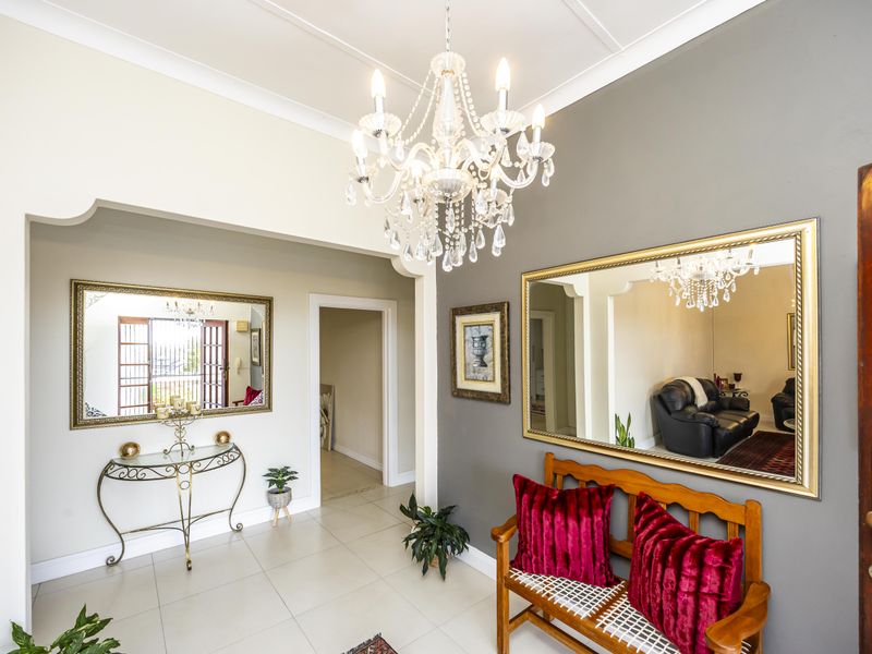 Welcoming entrance hall featuring tiled flooring, a decorative crystal chandelier, and elegant archway detailing leading into the home.
