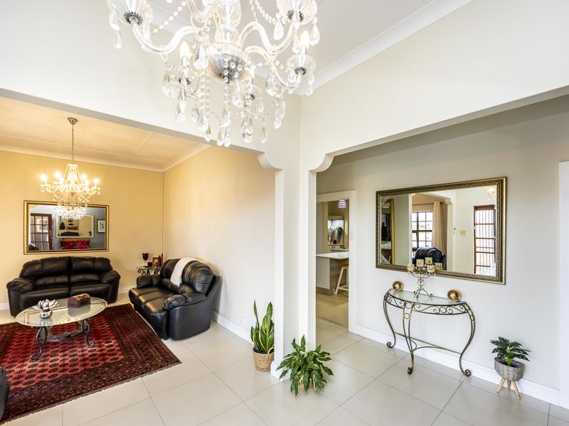 Spacious living area featuring elegant crystal chandeliers, tiled flooring, and architectural archways connecting to adjacent living spaces.