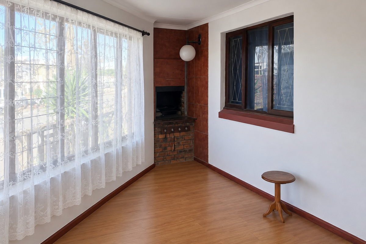A bright living area featuring laminate flooring, a built-in corner fireplace with brick detailing, and large windows with natural light.