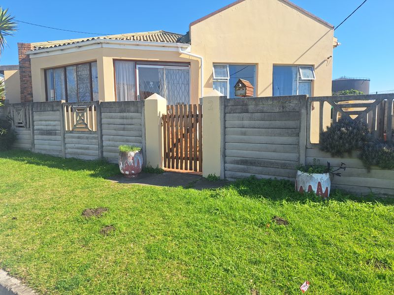 Front elevation of a single-story house featuring a precast concrete boundary wall, timber pedestrian gate, and tiled roof.