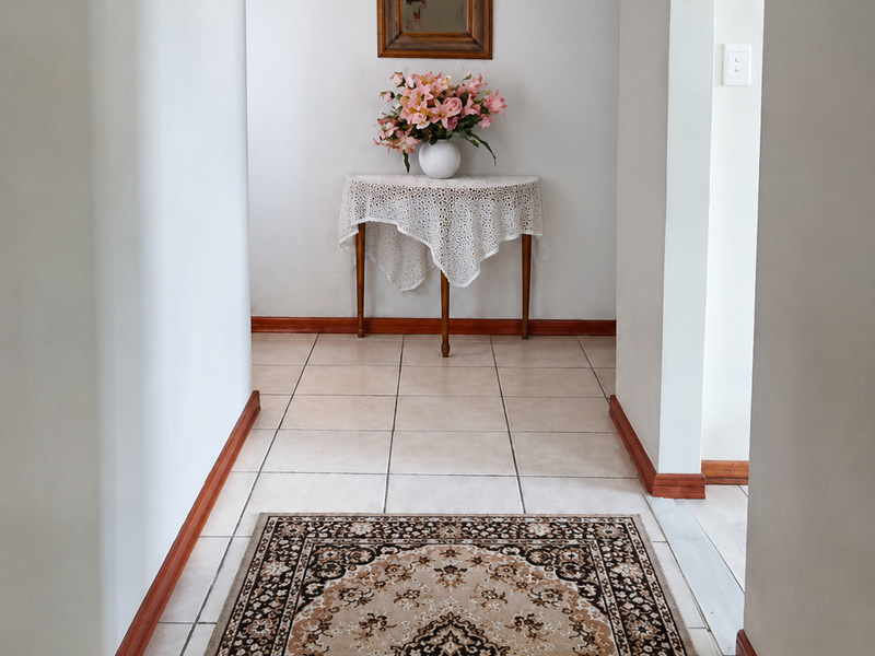 A bright hallway featuring neutral tiled flooring, timber skirting boards, and a distinctive arched entryway leading to adjacent living spaces.