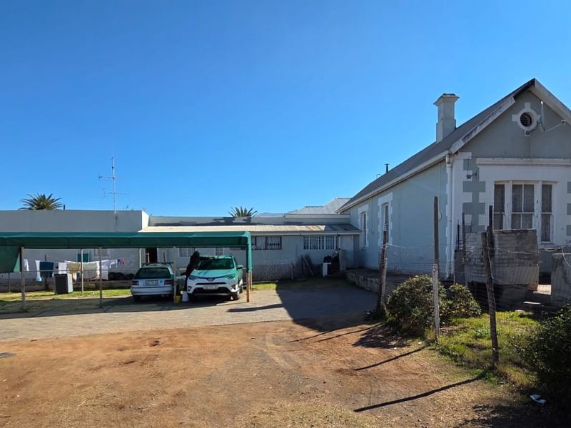 Front exterior view of a house featuring a paved driveway, a covered carport, and a traditional gabled roof structure with visible masonry details.