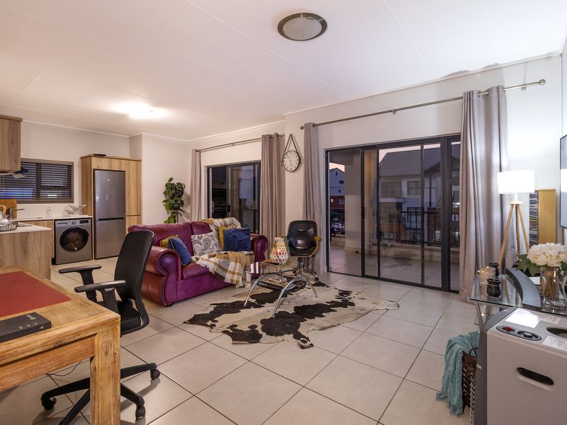 Open-plan living area featuring a modern kitchen with built-in cabinetry and large sliding glass doors leading to a balcony.
