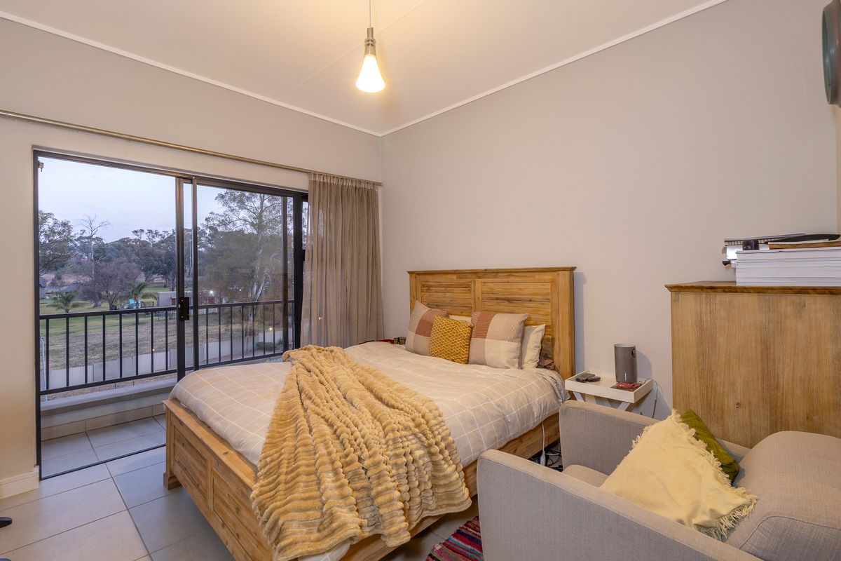 A well-lit bedroom featuring tiled floors and a sliding glass door that opens onto a private balcony with outdoor views.