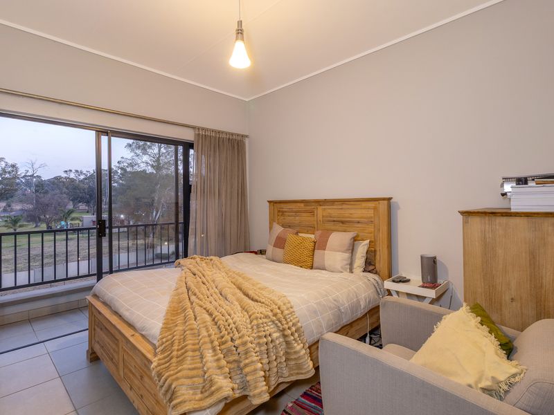 A well-lit bedroom featuring tiled floors and a sliding glass door that opens onto a private balcony with outdoor views.