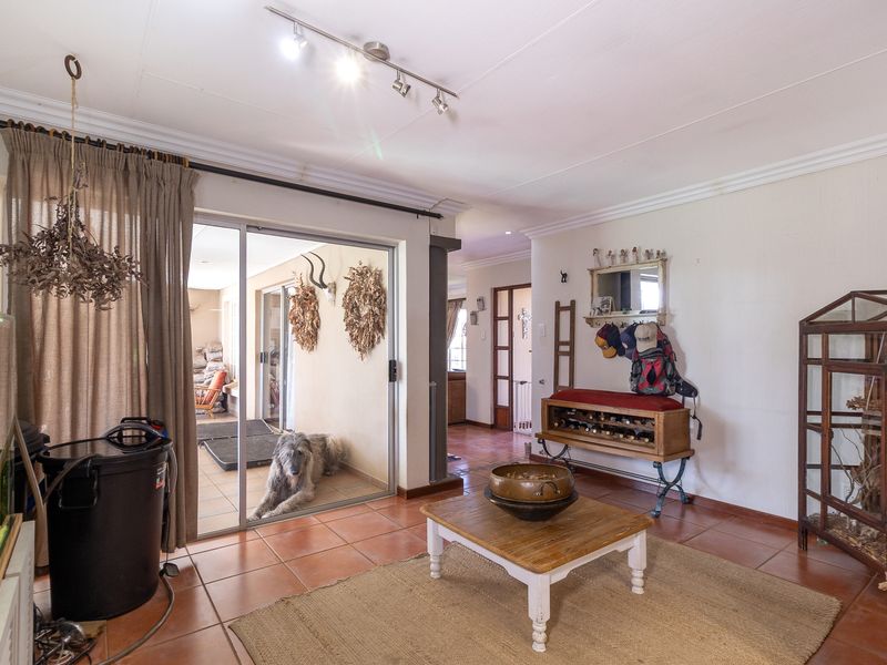 A living room featuring ceramic tile flooring, coved ceilings, and a sliding glass door providing access to an outdoor patio area.