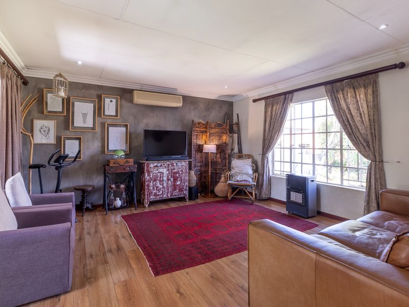 Spacious living room featuring laminate flooring, a split-system air conditioner, and large windows that provide ample natural light.